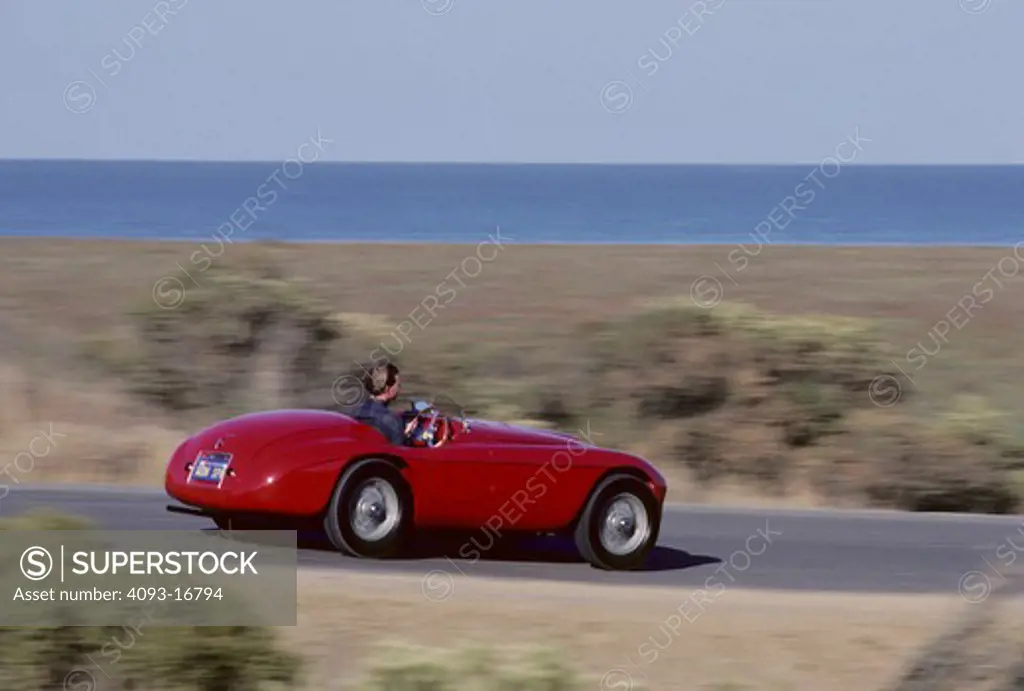 1951 Ferrari 166 MM Barchetta action rear 3/4 Lusso touring race car. The 166 MM Touring Barchetta, a Ferrari masterpiece, still increase pulse rates fifty-five years later. It is the first Ferrari sports car; all previous cars were strictly for racing. Craftsmen welded a tubular frame with a 2,200 mm wheelbase to hand-formed body panels. Beneath the hood resides a Colombo designed 1,995 cc 60-degree V-12. The 166 MM was arguably the world's fastest sports car in its day. In the heyday, it recor