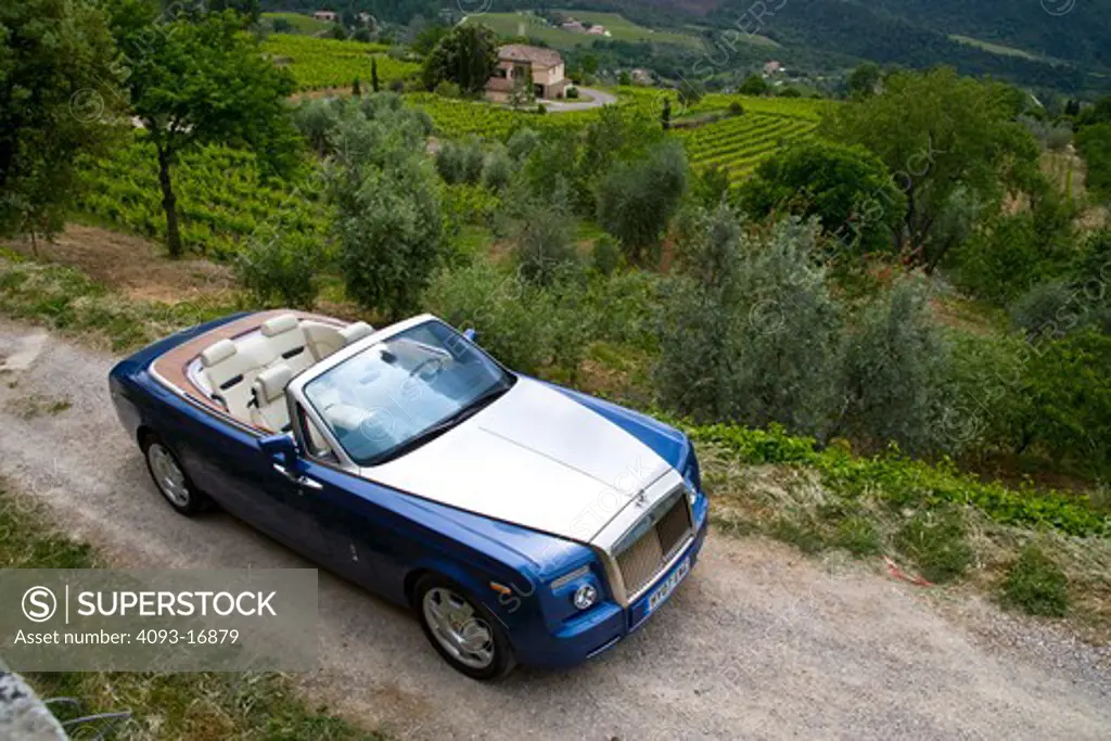 The Rolls-Royce Phantom Drophead Coupé is the latest convertible made by Rolls-Royce It has a 6.75 L, 48-valve, V12 engine that produces 453 hp  on an empty road in the hills of a vineyard nice residential area