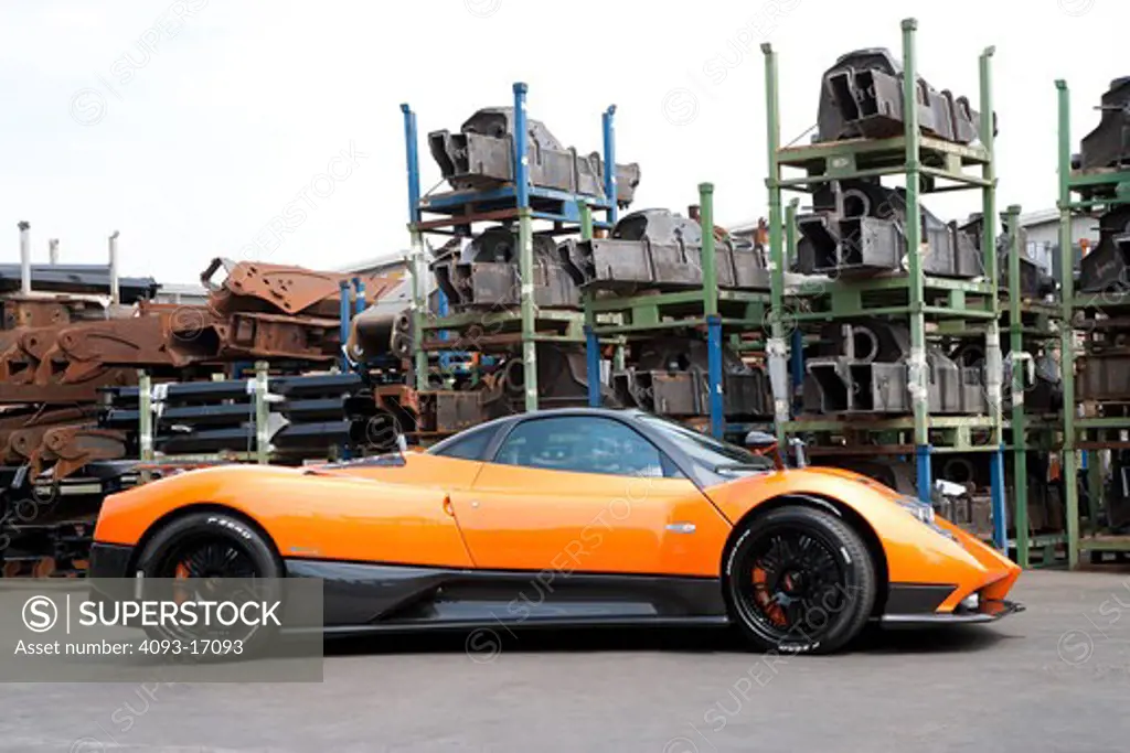 2005 Zonda F has a 7.3 L V12 a very fast 3.5 second sprint to 62 mph. Bright orange outdoors in a junkyard or industrial area