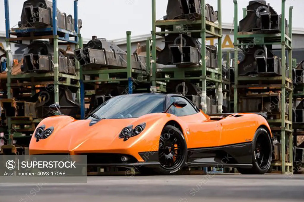 2005 Zonda F has a 7.3 L V12 a very fast 3.5 second sprint to 62 mph. Bright orange outdoors in a junkyard or industrial area