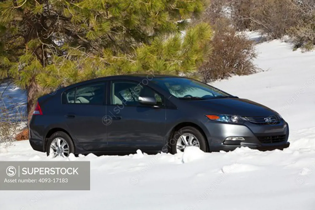 Front 3/4 view of a 2010 Honda Insight Hybrid on a snow lined rural road