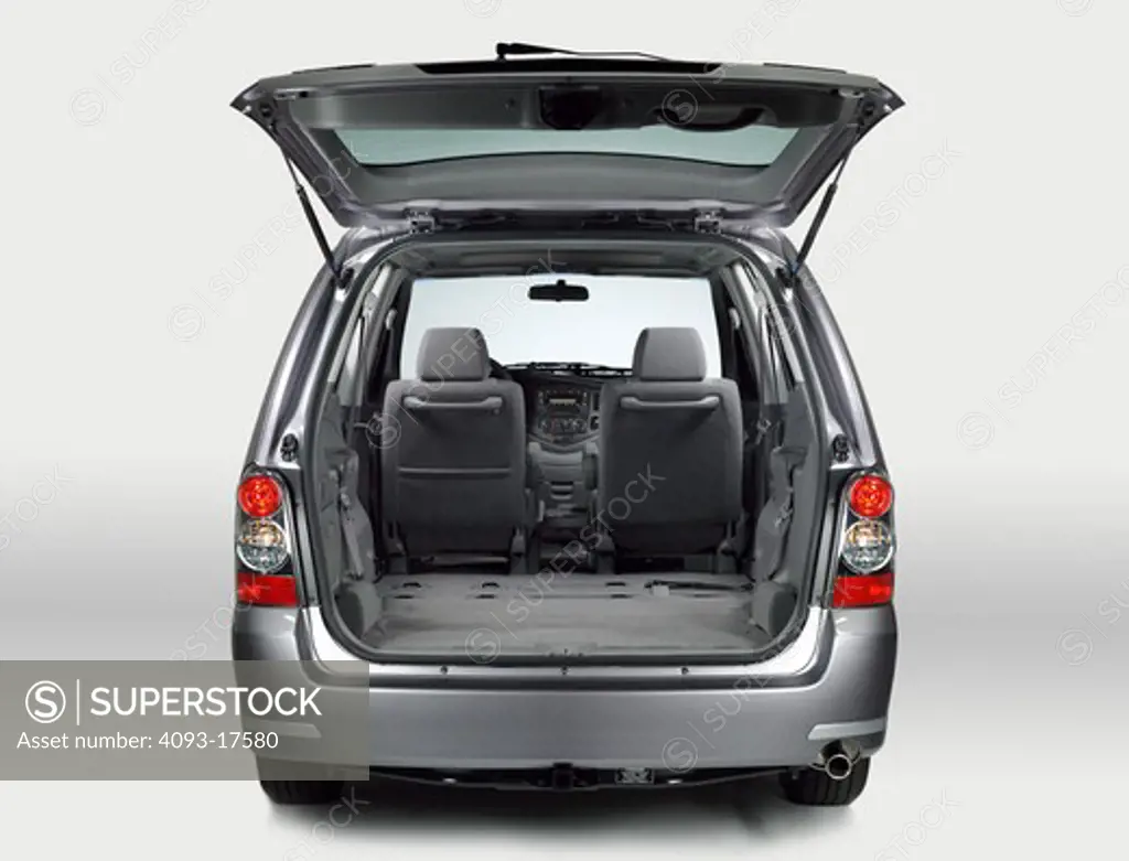 Rear view of a silver 2006 Mazda MPV minivan with the rear hatch open showing the cargo area with the back seats removed.