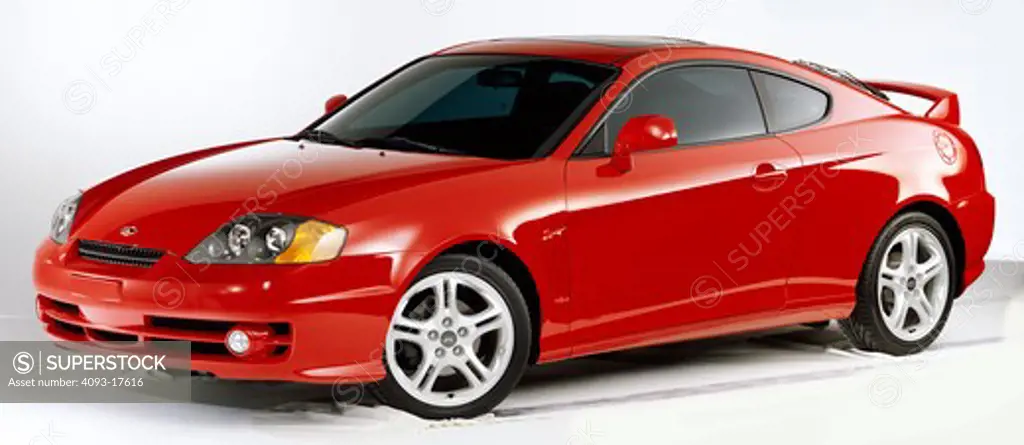Front 3/4 view of a red Hyundai Tiburon photographed in the studio with a white background.