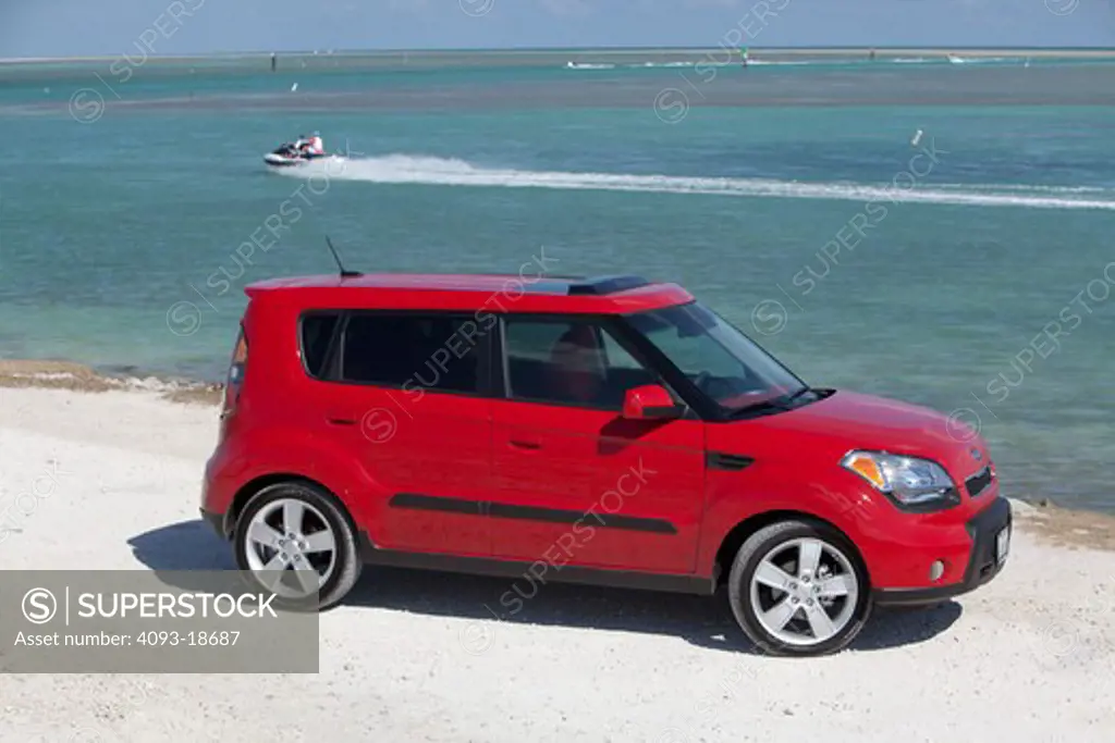 Front 7/8 static view of a 2010 red Kia Soul parked at the beach