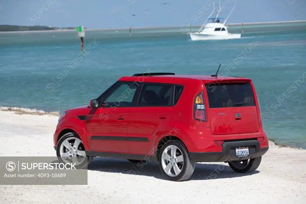 2010 red Kia Soul parked by sea, rear view