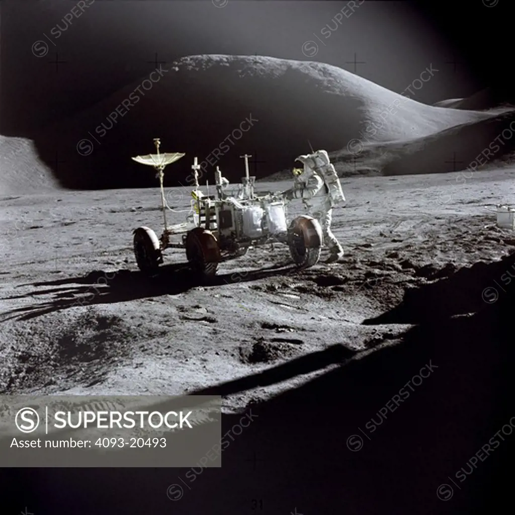 Astronaut James B. Irwin  Lunar Module pilot  works at the Lunar Roving Vehicle during the first Apollo 15 lunar surface extravehicular activity (EVA-1) at the Hadley-Apennine landing site. The shadow of the Lunar Module Falcon is in the foreground.