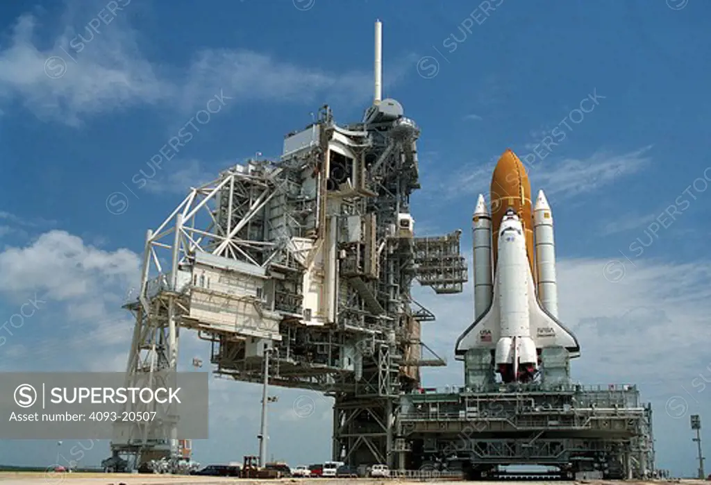 The Crawler Transporter brings the Space Shuttle Discovery on its Mobile Launcher Platform into position at Launch Pad 39B  following rollout from the Vehicle Assembly Building. The Fixed Service Structure and the Rotating Service Structure  permanent parts of the launch pad  are left of the Shuttle.