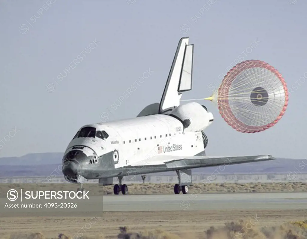 The Space Shuttle Atlantis lands with its drag chute deployed on runway 22 at Edwards, California.