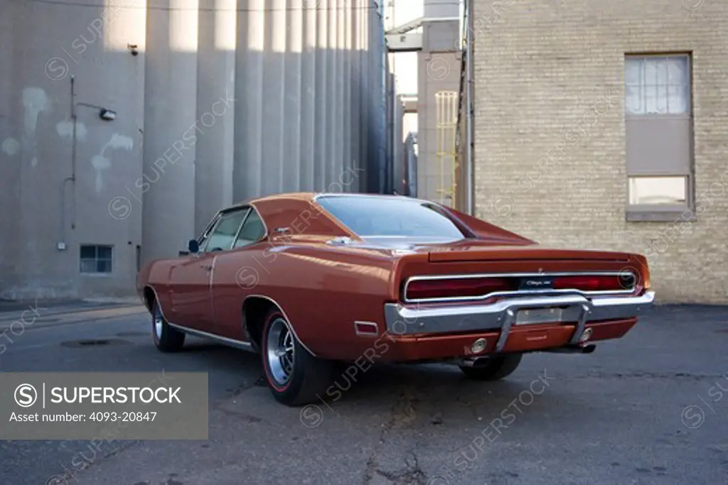 1970 red maroon 383 Dodge Charger next to a factory