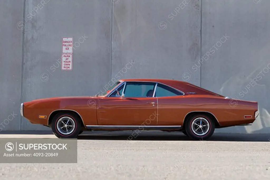 1970 red 383 dodge charger parked next to a concrete wall.