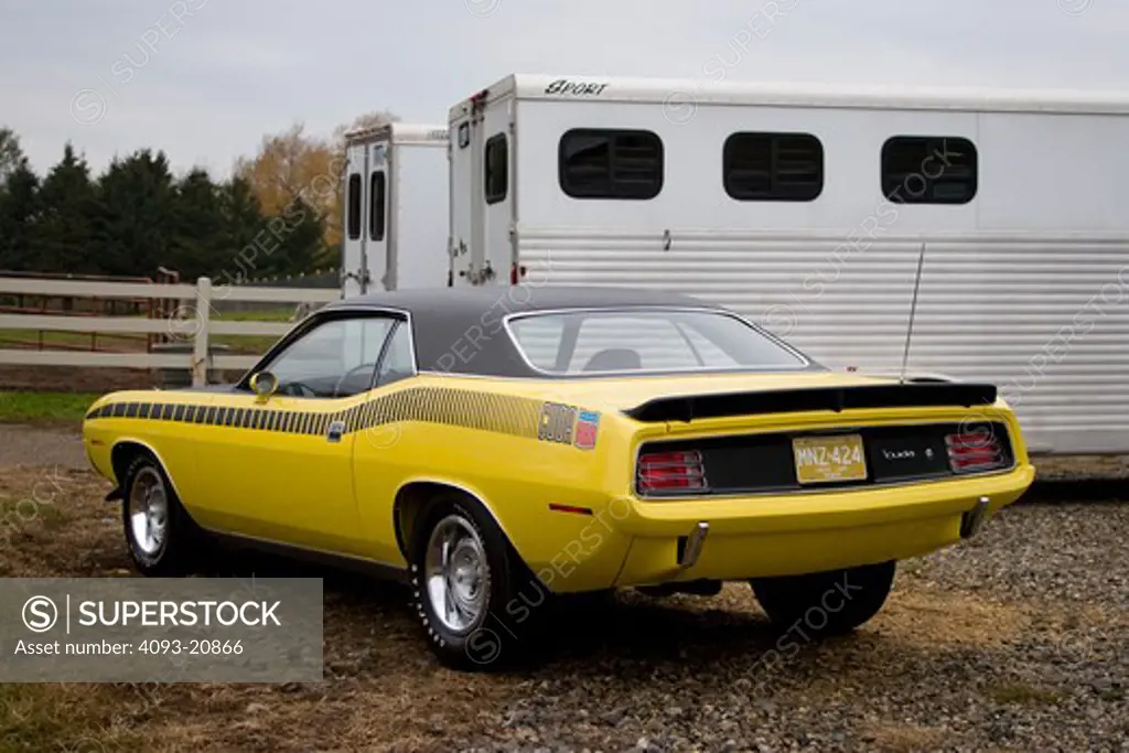 1970 plymouth AAR barracuda in the country next to a horse trailer