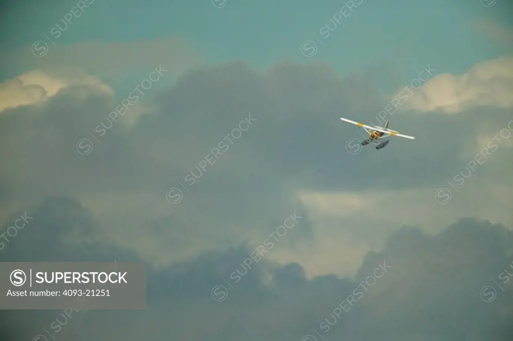 A deHaviland Beaver floatplane in flight. in the sky and clouds