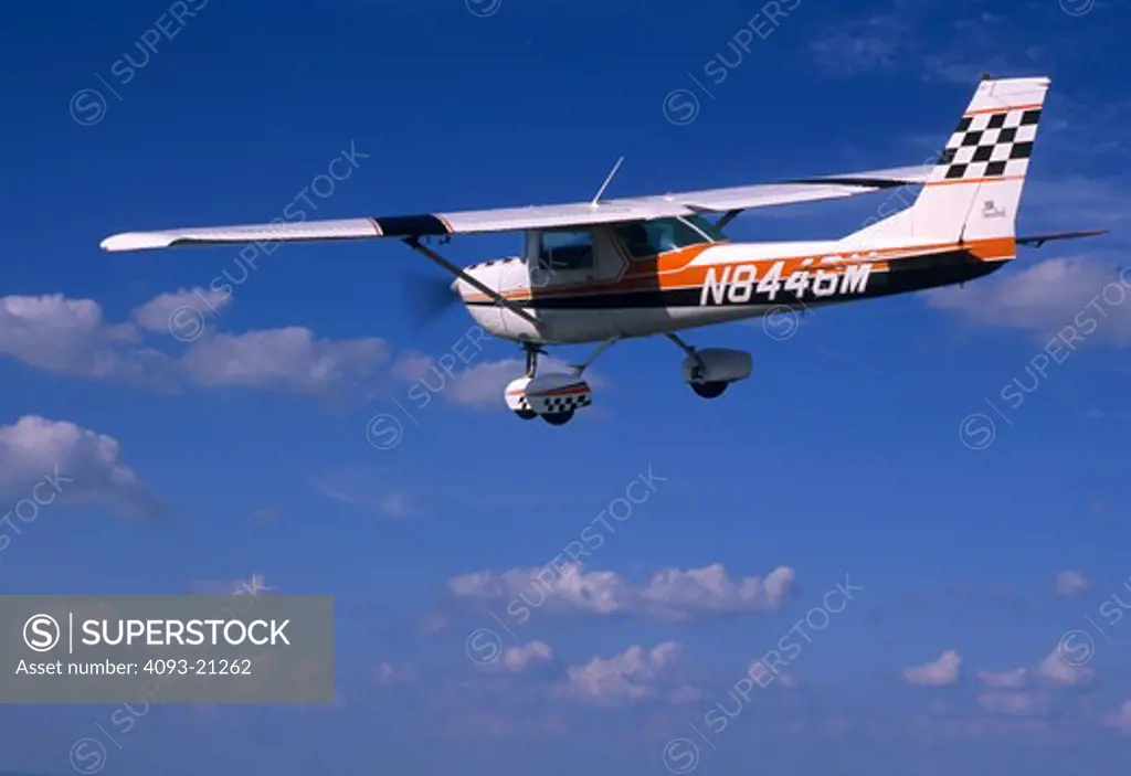 1970's Cessna C150 C 150 Aerobat. Built from 1970 to 1977. This variant of the Cessna 150 trainer is structurally enhanced for limited +6/-3g aerobatics. The Aerobat features skylights  four point harnesses  G-meter  quick jettison doors  and removable seat cushions so parachutes can be worn. This particular plane is flying over a midwestern town.