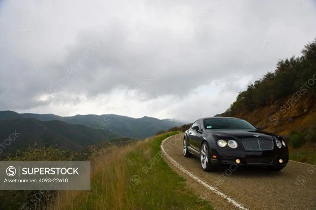 2009 black Bentley Continental GT on a rural mountain road.