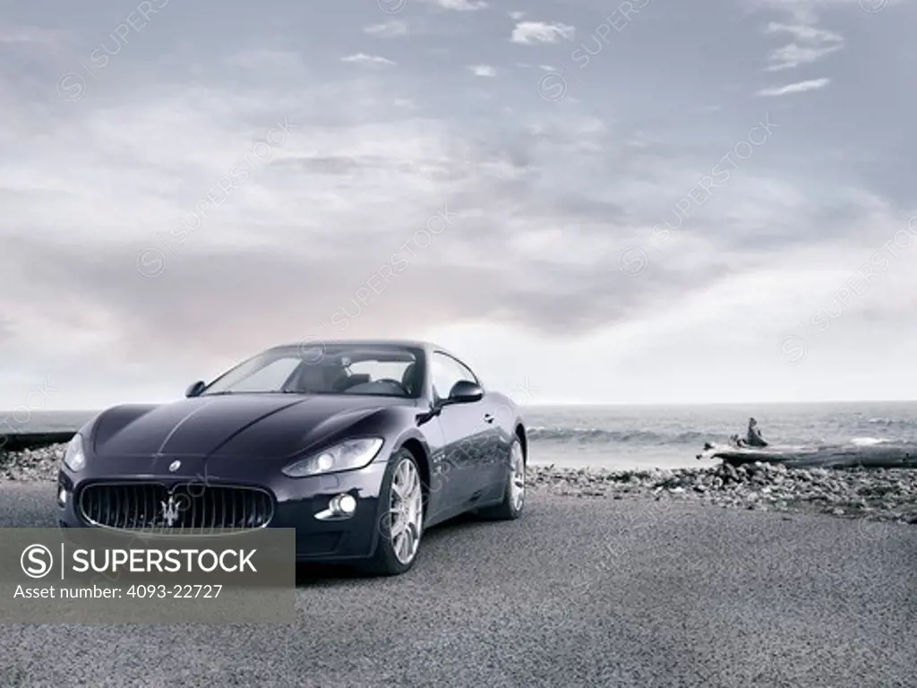 Front 3/4 view of a 2009 Maserati GranTurismo S sports coupe at a deserted beach.