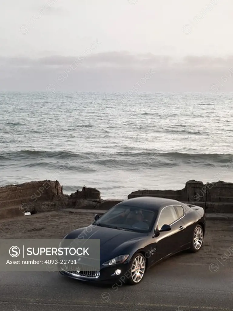 High front 3/4 view of a 2009 Maserati GranTurismo S sports coupe at a deserted beach.