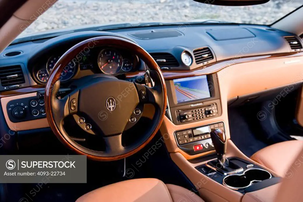 Interior view of a 2009 Maserati GranTurismo S sports coupe showing the steering wheel, instrument panel IP, shifter, dash, dashboard, ventilation system and GPS Navigation System.