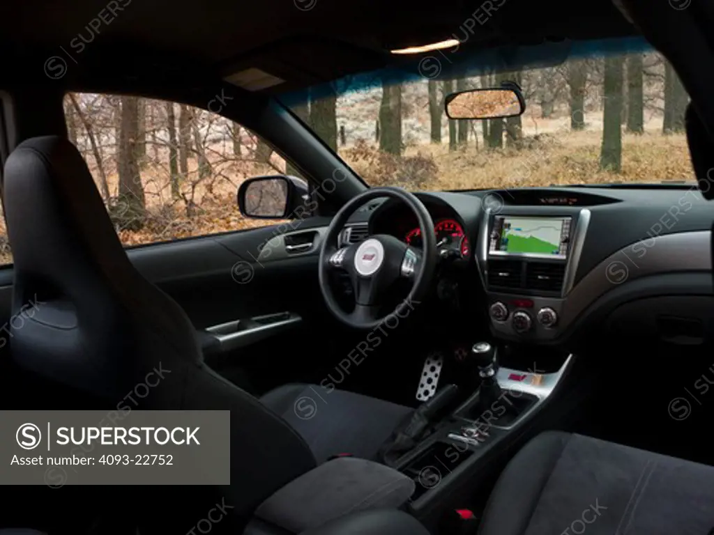 Interior view of a 2009 Subaru Impreza WRX STi showing the front seats, steering wheel, instrument panel ( IP ), shifter, ventilation system and GPS Navigation Display.