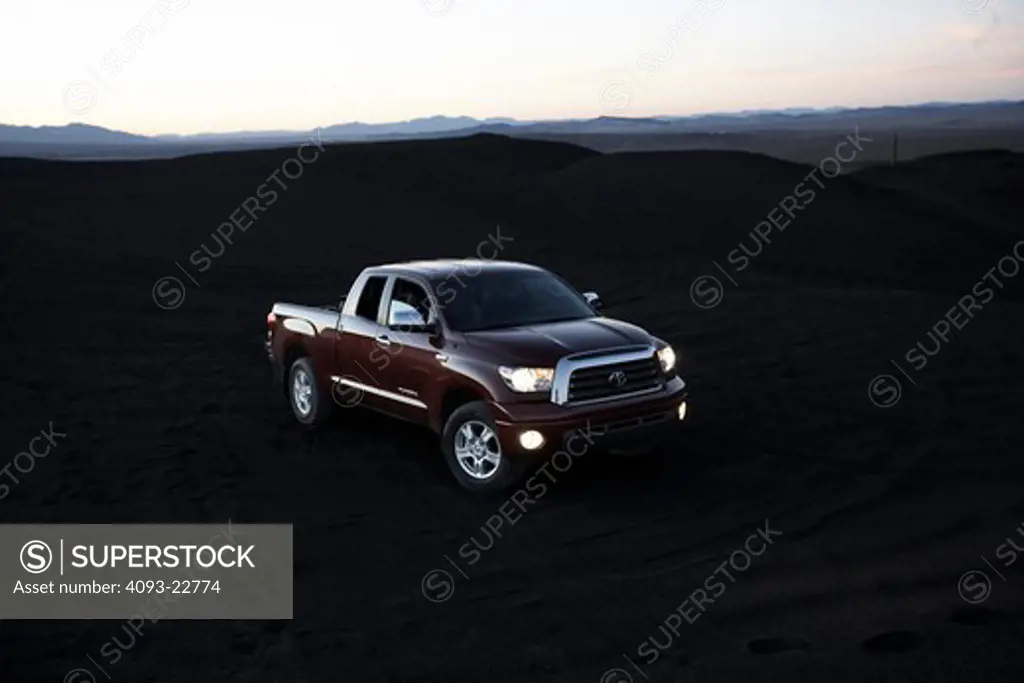 Front 3/4 static view of a 2009 Toyota Tundra on black sand volcanic rock in a rural location.