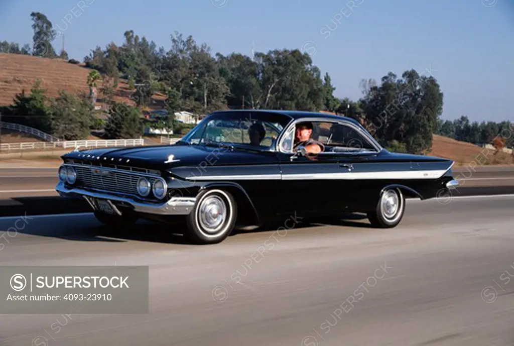 1961 Chevrolet Impala SS Front 3/4 action of a black 1961 Chevrolet Impala SS on a public highway.