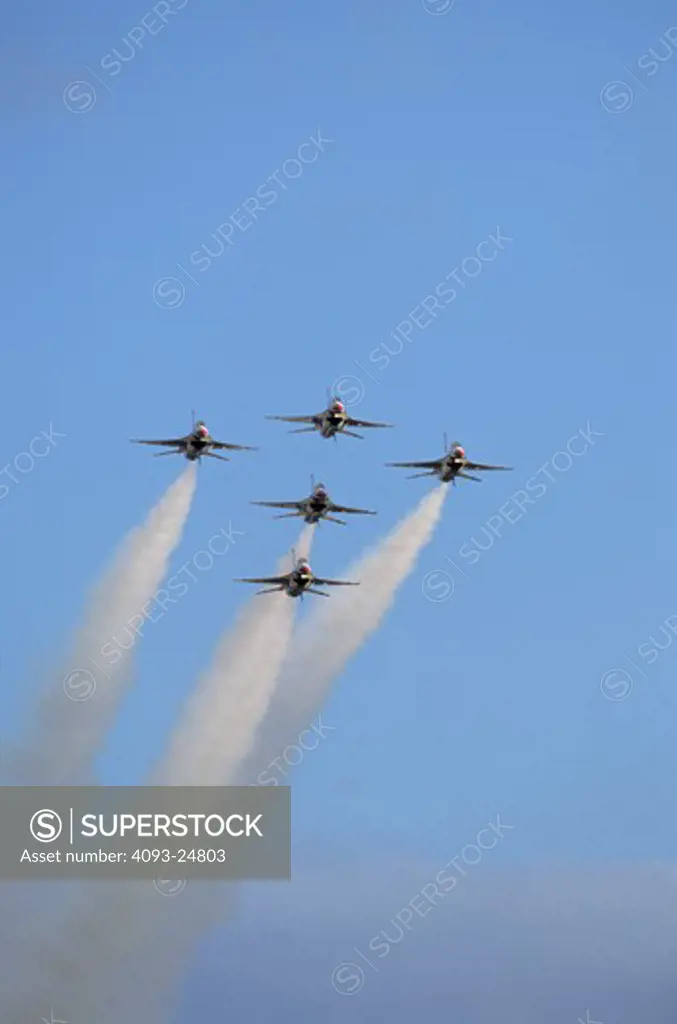 A head-on view of the USAF Thunderbirds with smoke on. Five-ship arrow-head.