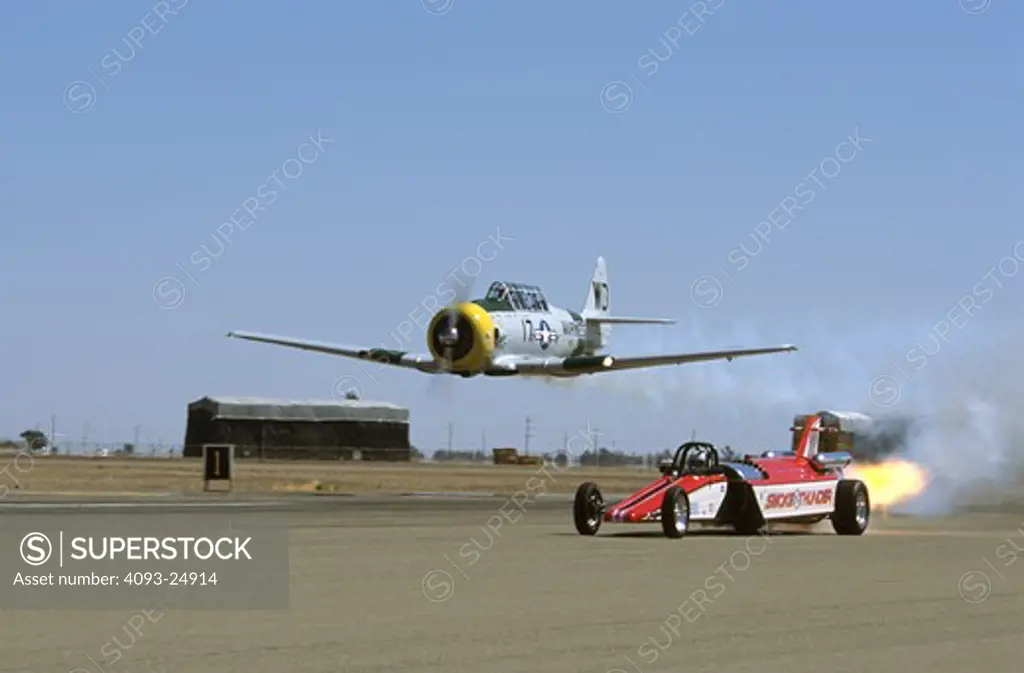 John Collver in his North American SNJ (T-6) War Dog races Scott Hammack in his Smoke and Thunder jet car during the El Centro Air Show, CA.