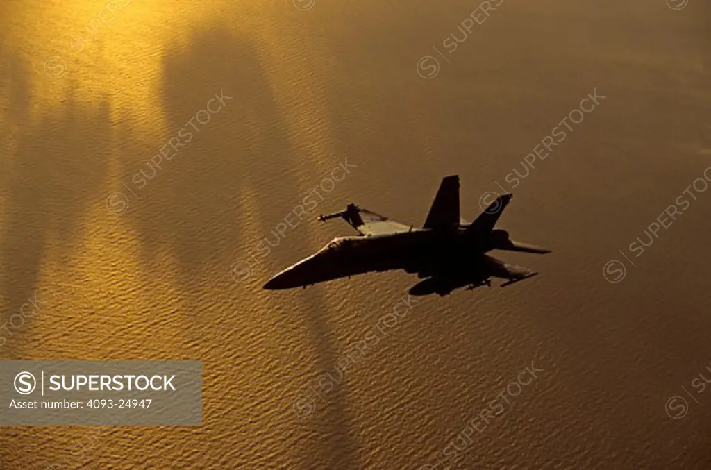 Moody golden sunset shot of a US Navy F/A-18C Hornet over the Pacific Ocean