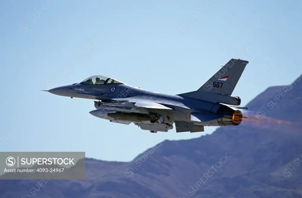 Danish / Denmark Air Force Lockheed F-16 Fighting Falcon Viper taking off in full afterburner with mountains in background  carrying live ordnance; two thousand (2 000) pound bombs.