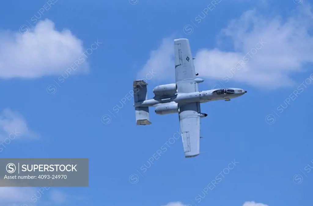 Top planform view of USAF A-10 Thunderbolt II Warthog against blue sky with a few puffy white clouds
