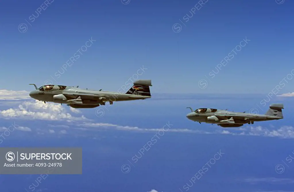 Two / pair of US Navy Grumman EA-6B Prowlers Above the Pacific Ocean some clouds side view of both aircraft