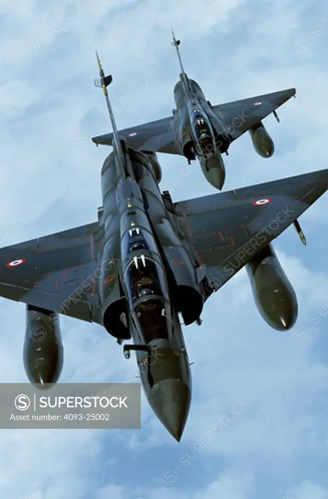 A pair  two  formation of French Air Force Dassult Mirage 2000D fighter bombers in dark green camouflage over clouds