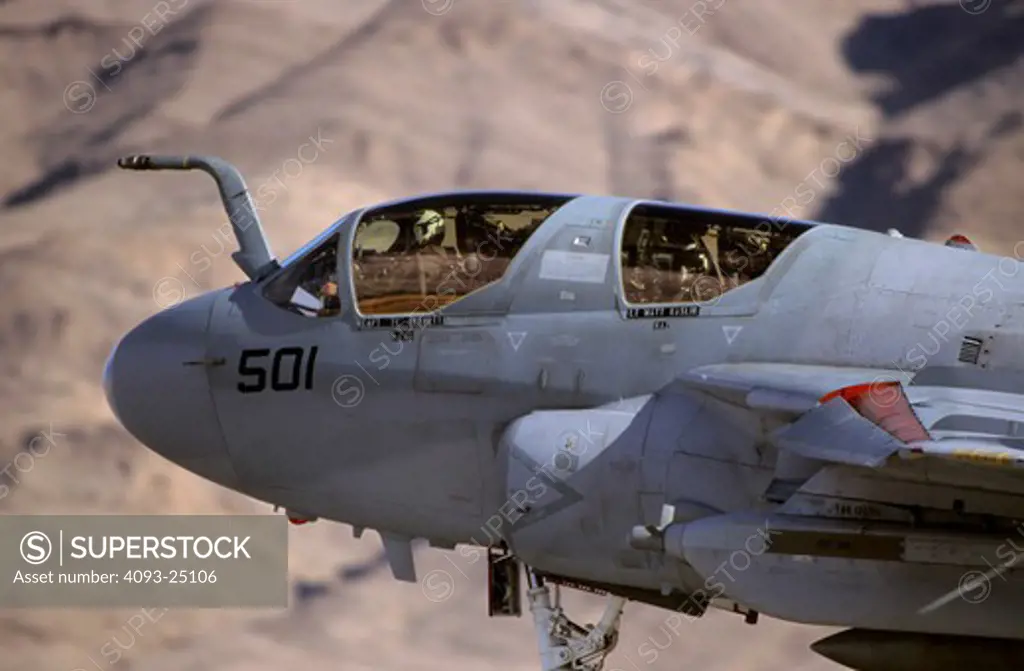 Tight close-up shot US Navy Grumman EA-6B Prowler electronics warfare aircraft departs the runway and retracts is landing gear. Hills/mountains in background