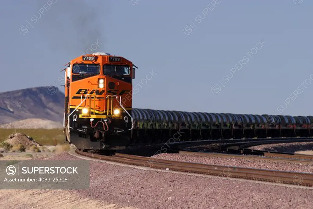 BNSF diesel electric locomotive # 7789 manufactured by General Electric model ES44DC at Goffs California with a coil steel train in tow. Diesel locomotives move through Union Pacific's West Colton freight yards Train passing through in motion