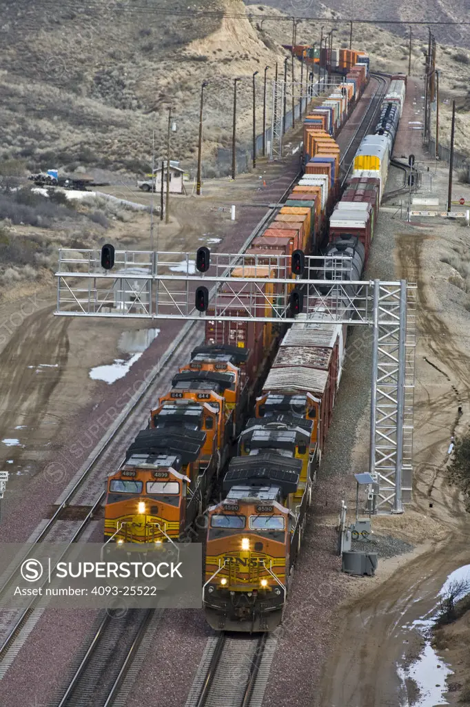 Two westbound 2005 BNSF freight trains cresting the top of a summit, side by side, high angle view