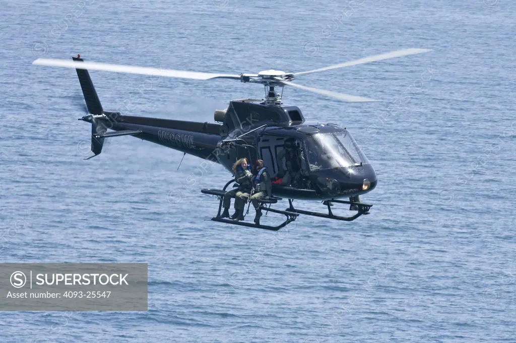 Eurocopter AS350 Ecureuil A-Star Helicopter flying over the Pacific Ocean near Malibu, CA during a Fast Rope type military operation.