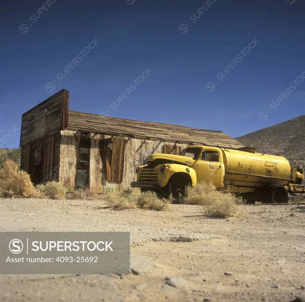 low angle yellow 1948 1940s tanker broken down rust abandoned old building wood