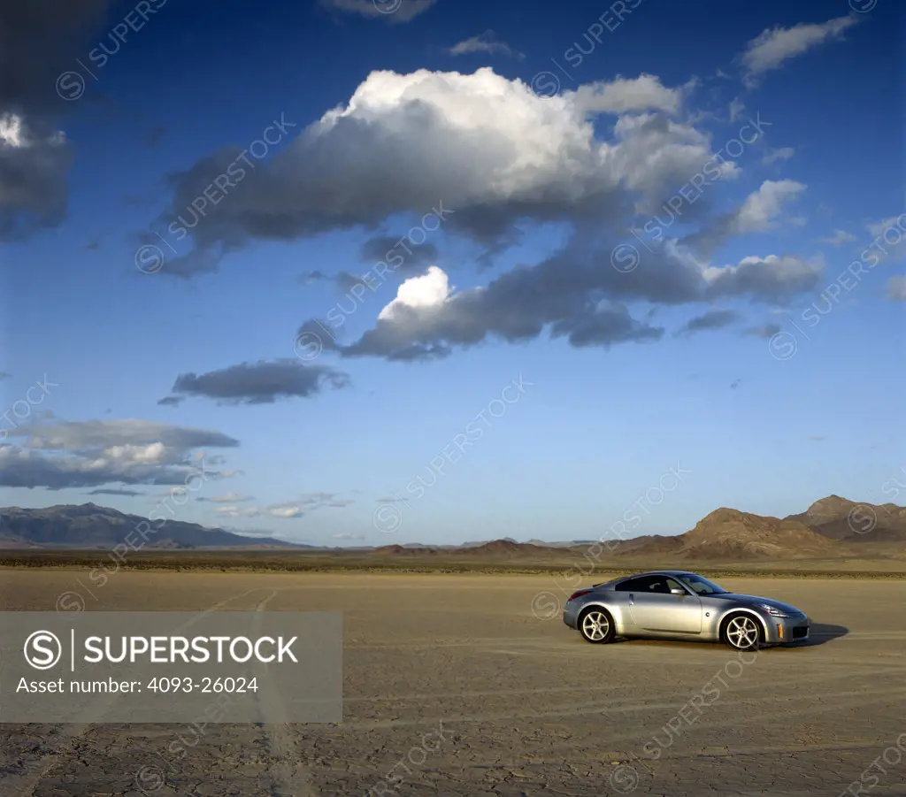 2004 Nissan 350Z in the desert dry lake bed salt flats with dramatic sky and clouds