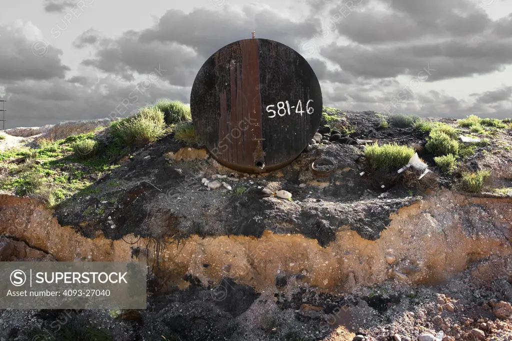 large barrel left and abandoned in the destert with plants and clouds.  vehicles in baja california, in the desert