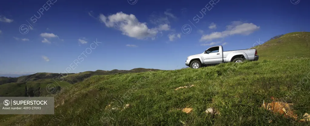 2007 Toyota Tacoma in an empty field overlooking a meadow hills mountains on a clear sunny day