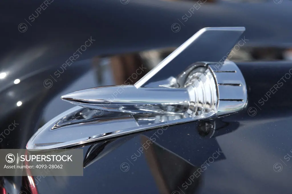 A close up detail shot of a chrome emblem on a 1957 Chevrolet Bel Air above the front headlight