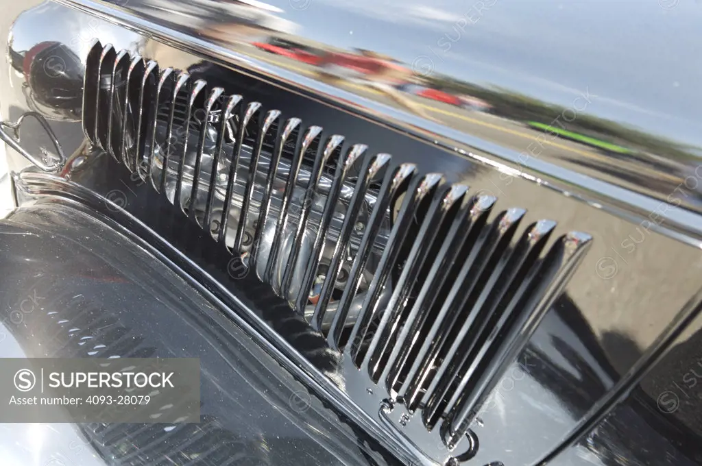 A close up detail shot of a chrome hood vent for an old hot rod