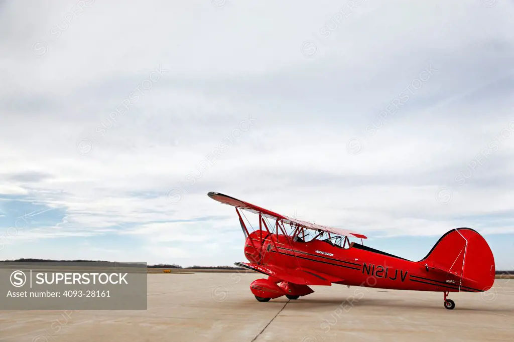 Red 2010 Waco YMF-5D on rural airport ramp, side view