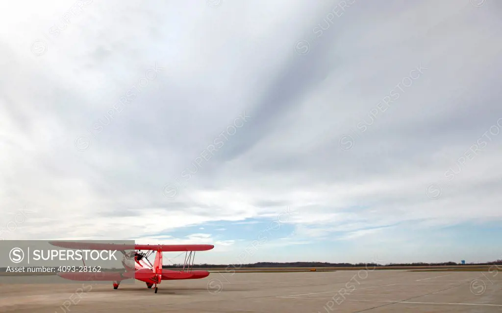 Red 2010 Waco YMF-5D on a rural airport ramp, rear 3/4