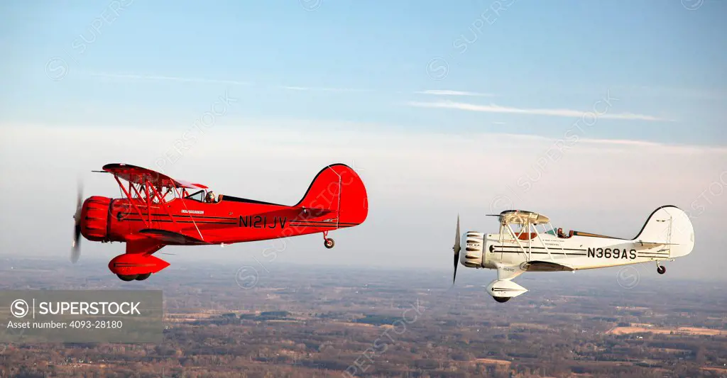2010 WACO YMF-5D and WACO owned test aircraft flying over countryside, side view