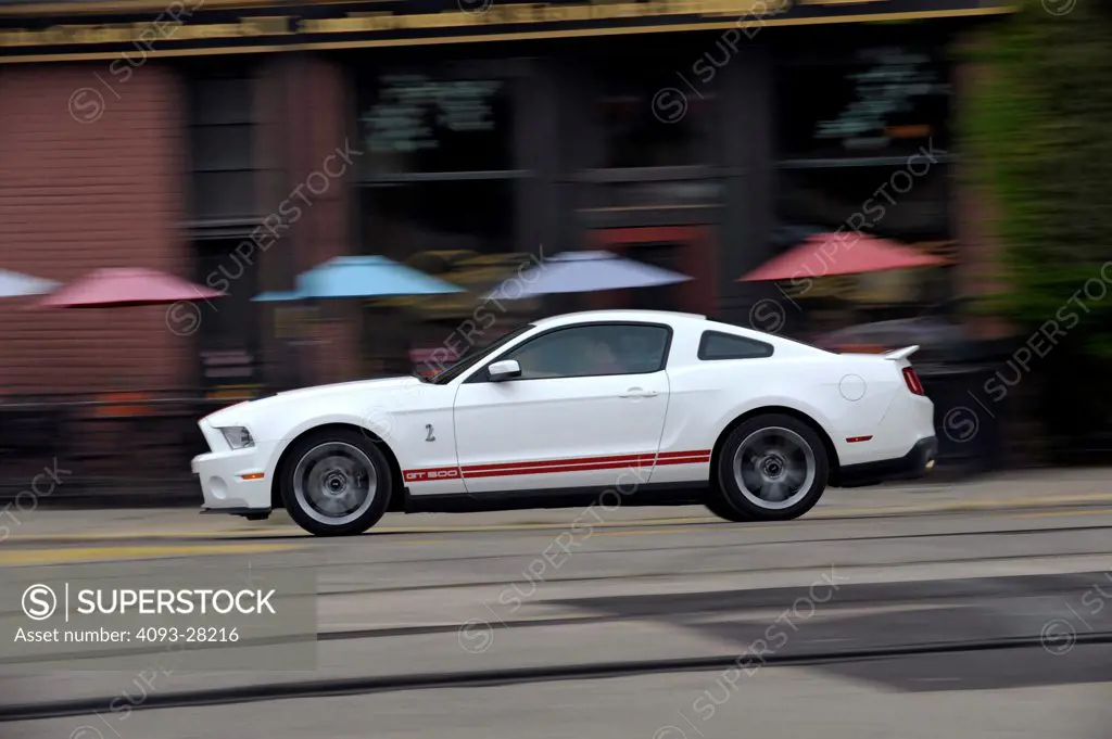 2010 Ford Mustang Shelby GT500 driving on urban city street, side view