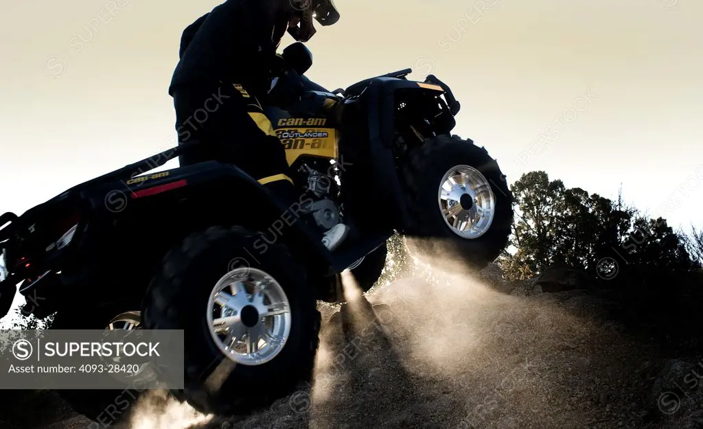 Rear 3/4 action of a 2010 Can-Am Quad ATV on a rural, tree lined trail