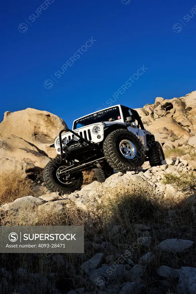 Front 3/4 action of a highly modified 2011 Jeep Wrangler off roading on a very rocky, rural mountain trail
