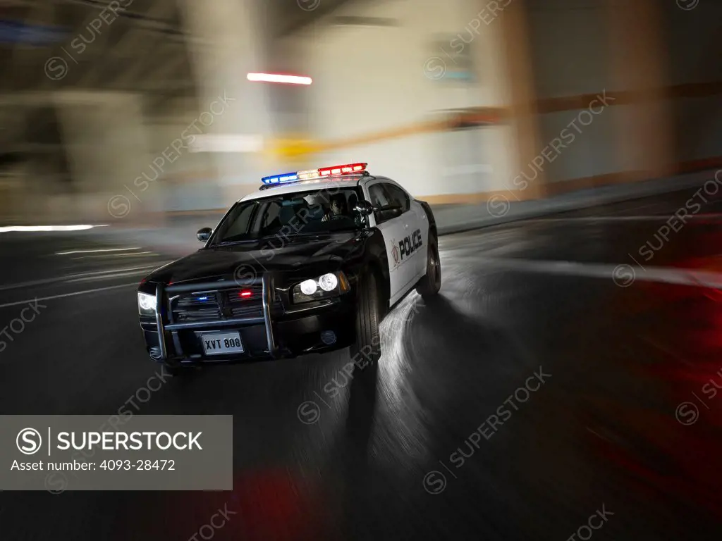 Front 3/4 action of a black and white 2010 Dodge Charger Police Interceptor on an urban street at night