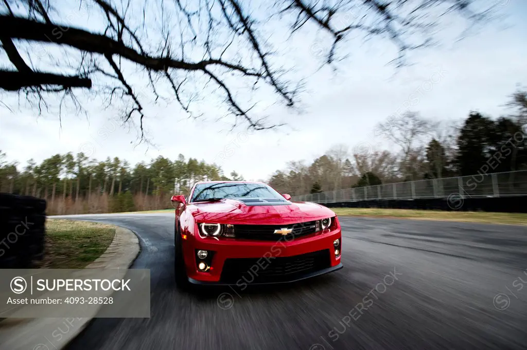 Straight on nose action of a red 2013 Chevrolet Camaro ZL1 on a rural race track