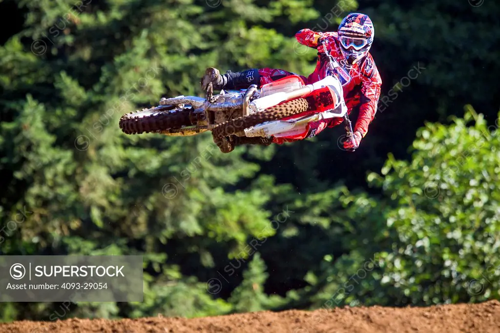 2008 Honda CRF 450R with rider Ivan Tedesco on dirt track course in forest, jumping, mid air, front view